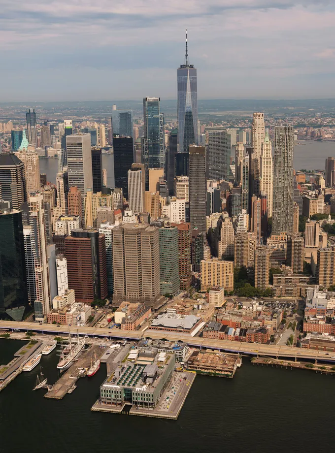 Aerial view of the Lower Manhattan skyline and One World Trade Center rising above the East River piers