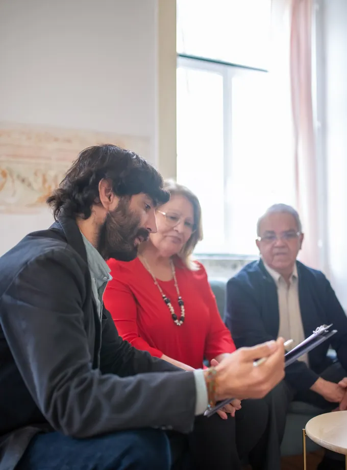Insurance advisor reviewing documents on a clipboard with an older couple seated on a sofa at home