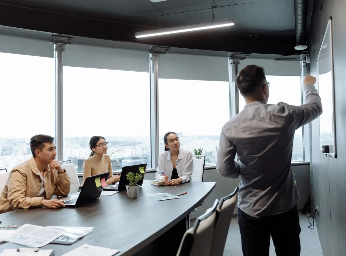 Colleagues in a meeting room discussing a presentation with city views