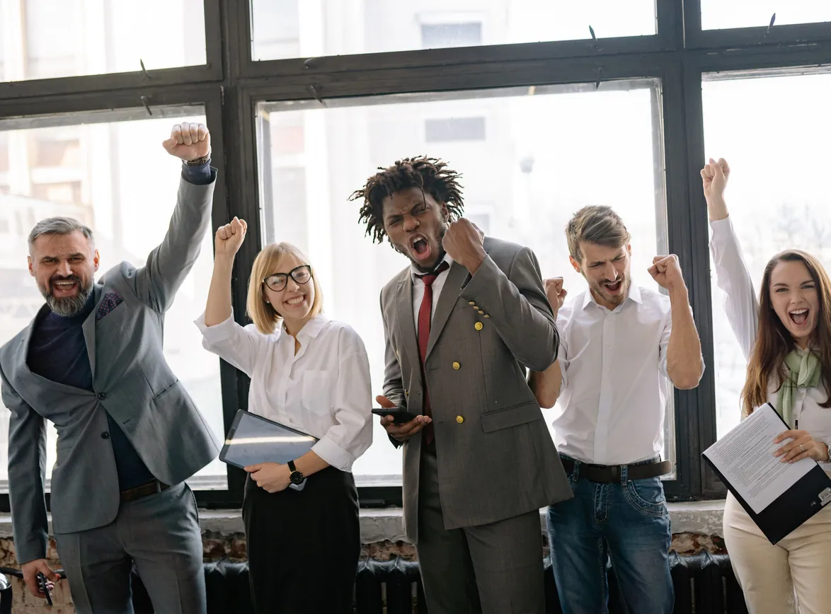 Group of professionals celebrating achievement in office setting with enthusiasm