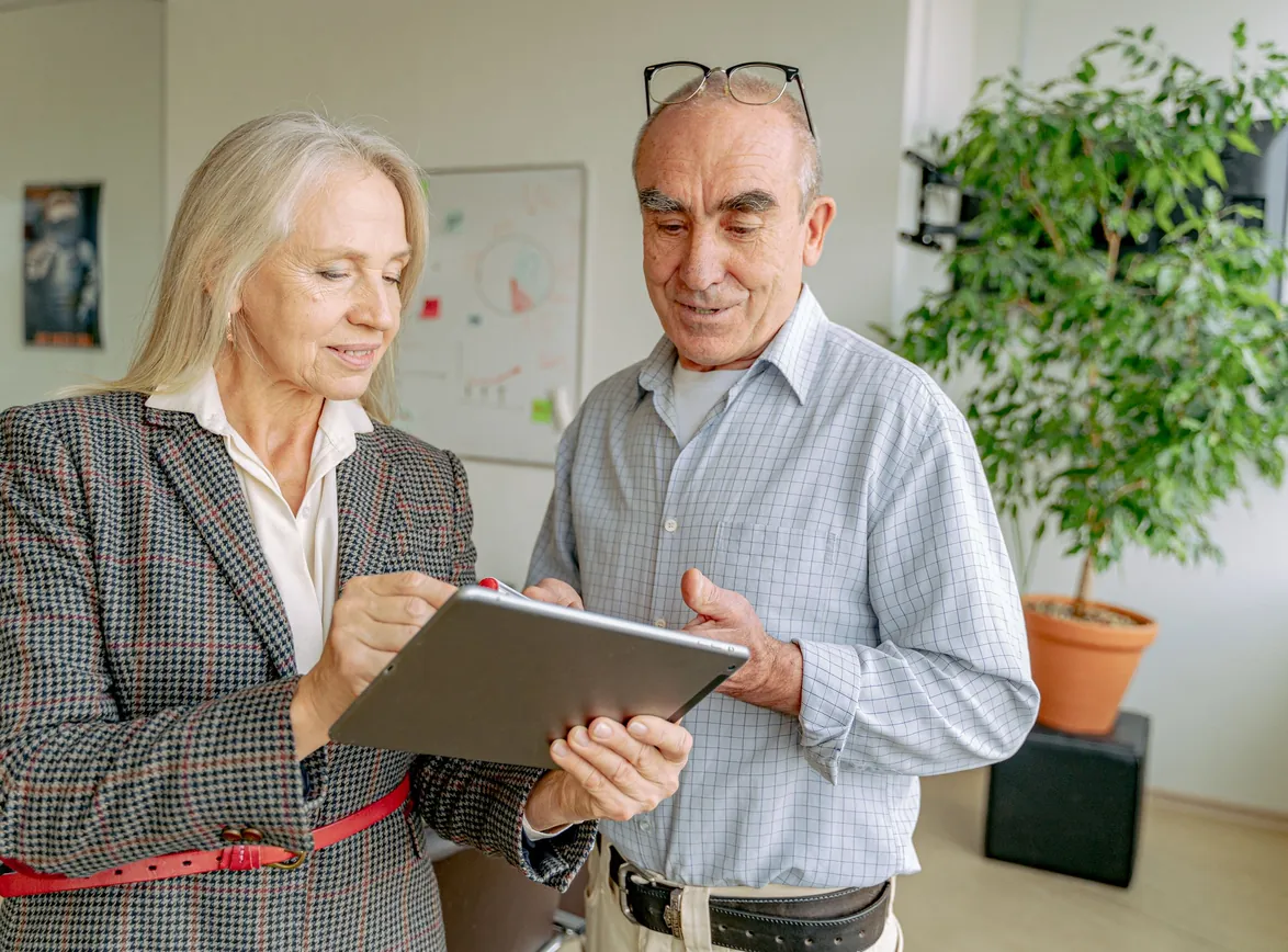 Senior professionals collaborating on a project using a digital tablet in a modern office setting