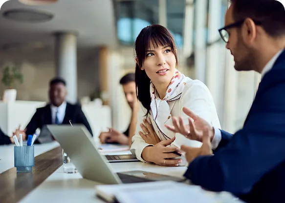 Businesswoman listening as a colleague in a navy suit explains a point during a meeting at a conference table