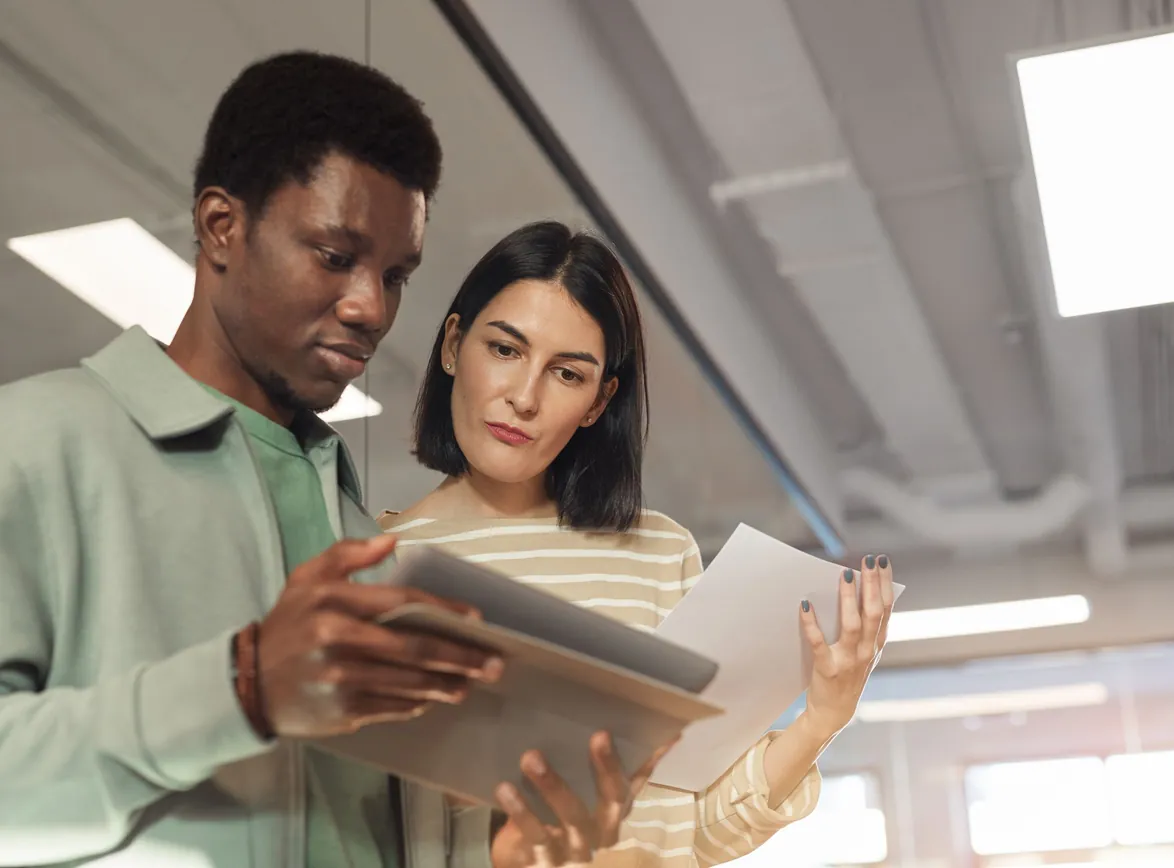 Two professionals collaborating on a project using a digital tablet in a modern office setting