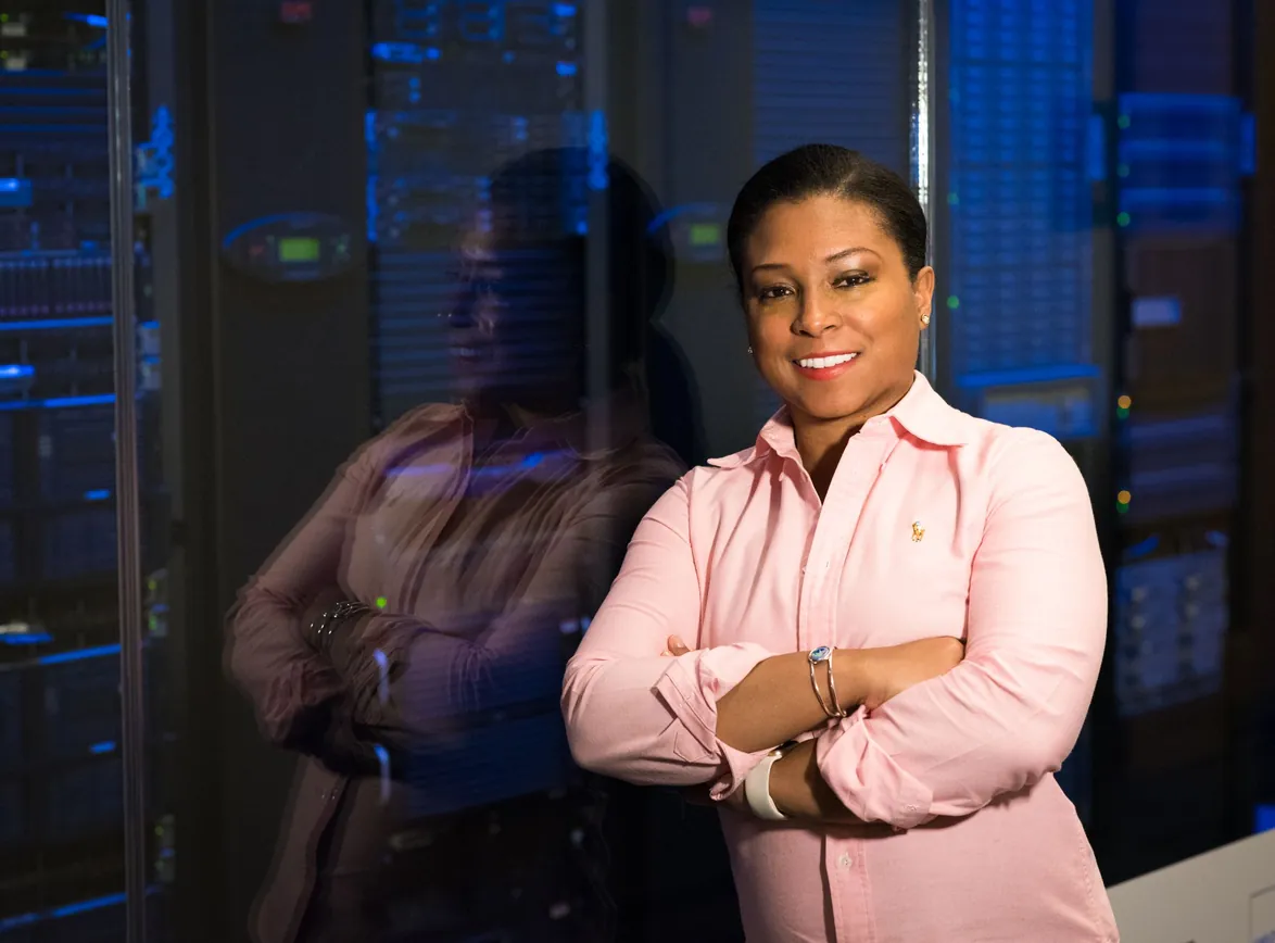 Smiling IT professional with crossed arms in a server room