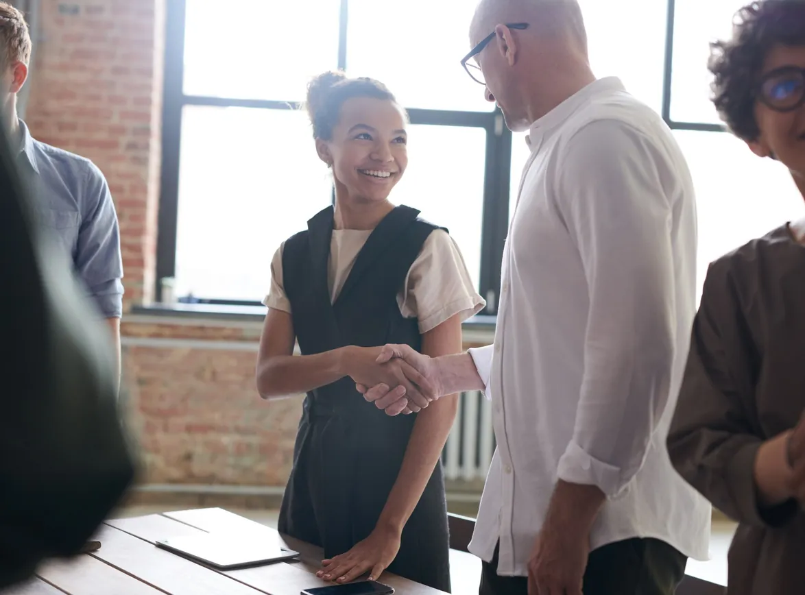 A group exchanging a handshake in a bright, modern office environment