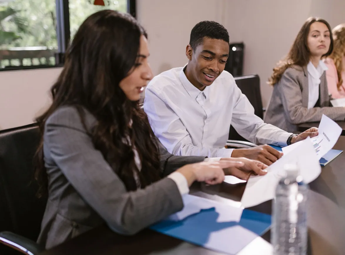 Colleagues reviewing printed reports together at a conference table during a team meeting