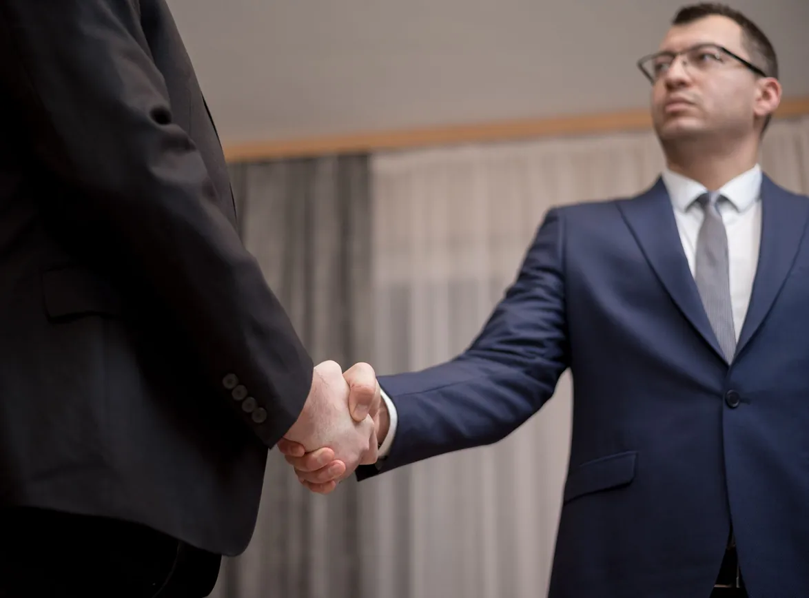 Two businessmen in formal attire shaking hands during a meeting
