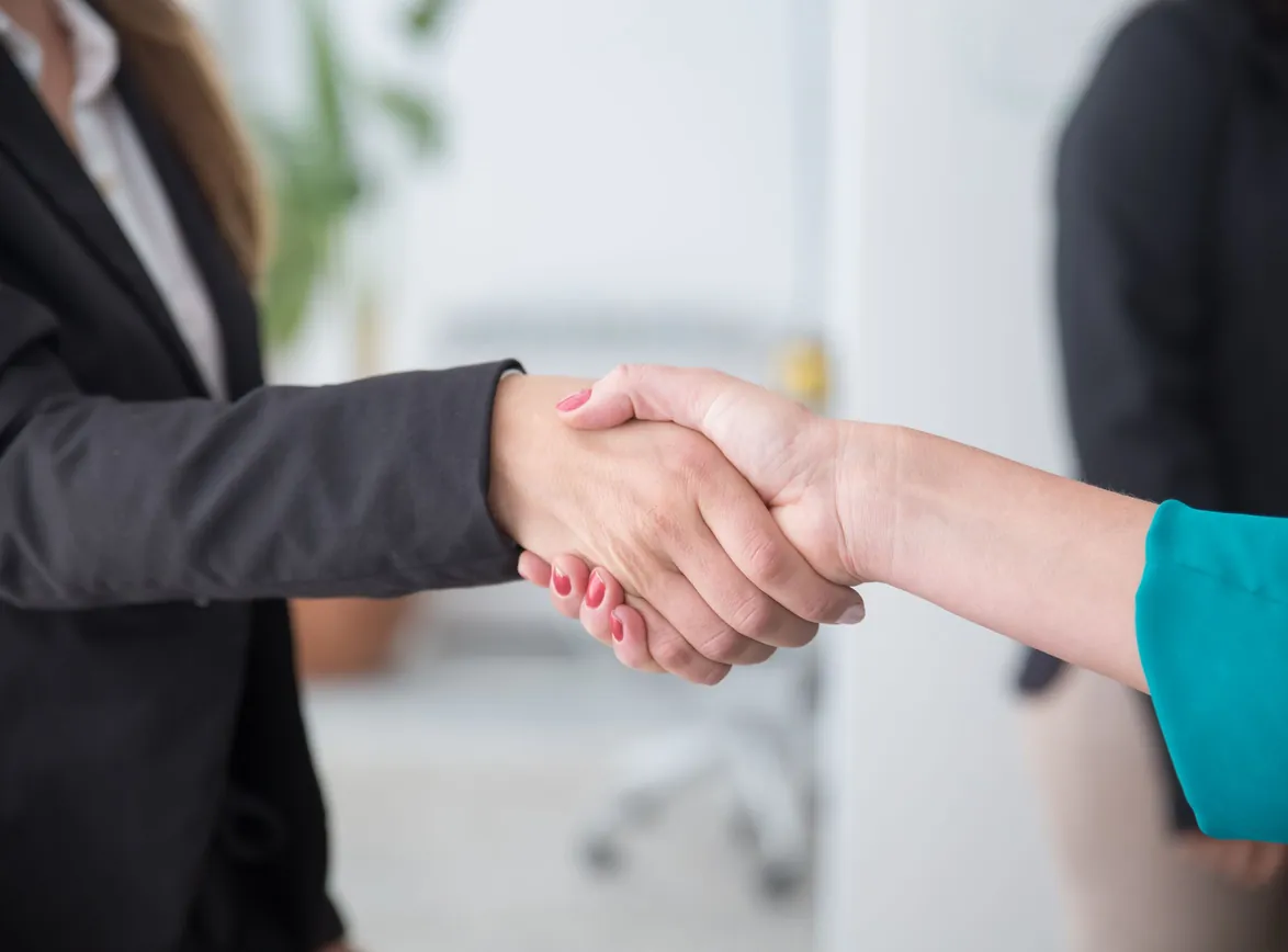 Close-up of a professional handshake between businesswomen in an office environment