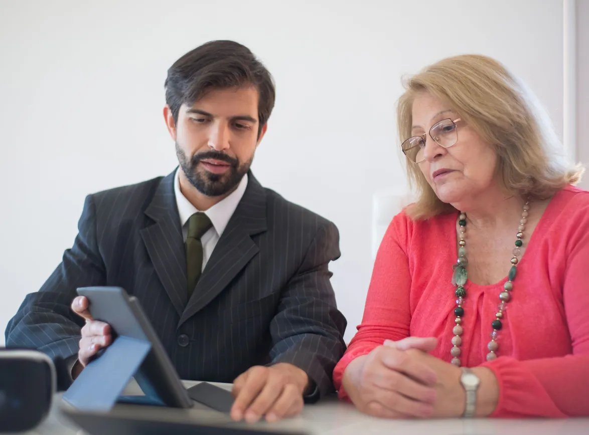 Business meeting between a man and senior woman discussing with tablet
