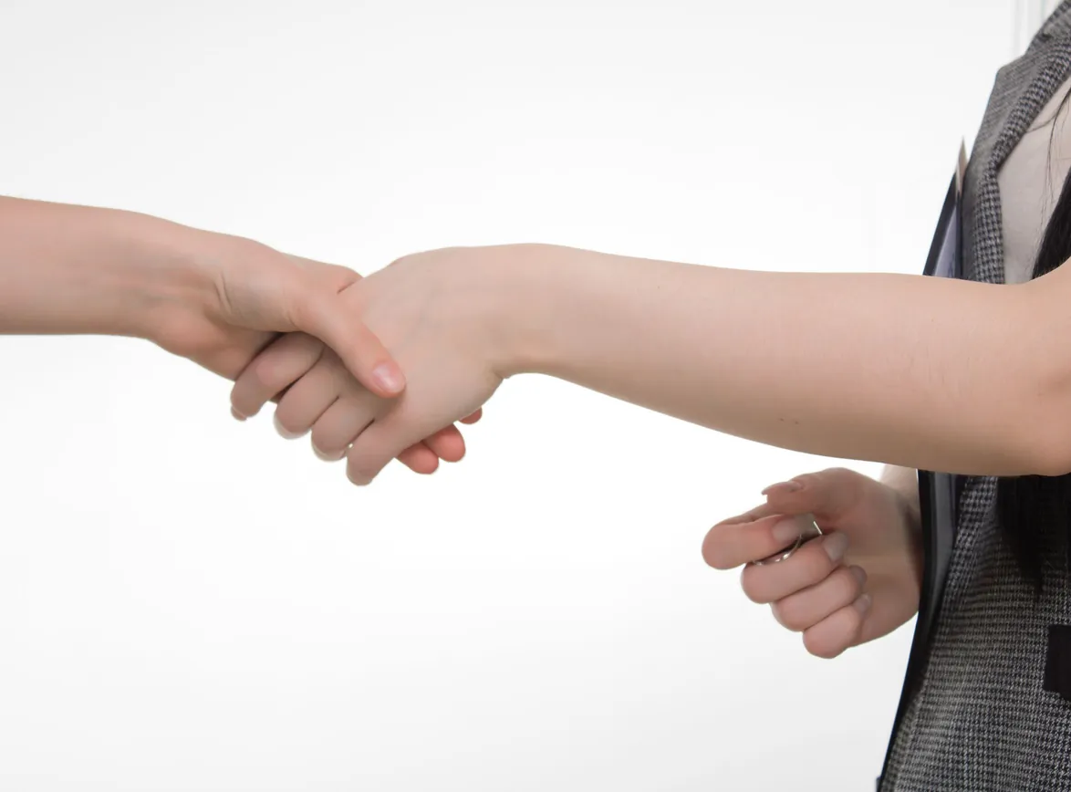 Close-up of two people shaking hands in a professional setting against a white background
