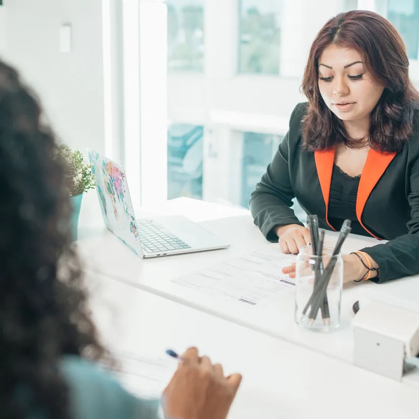 Financial advisor reviewing a form at her desk with a client seated across from her