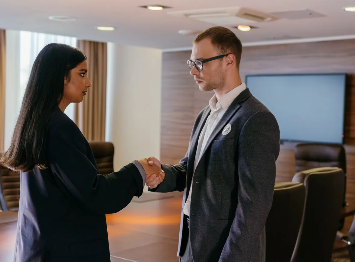 Two professionals shaking hands in a modern conference room