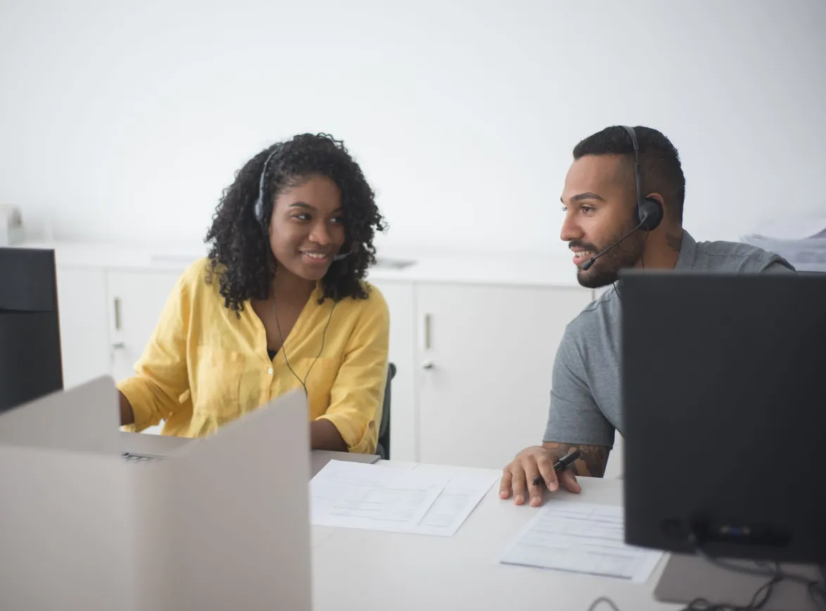 Two call center agents working together with headsets in a modern office environment