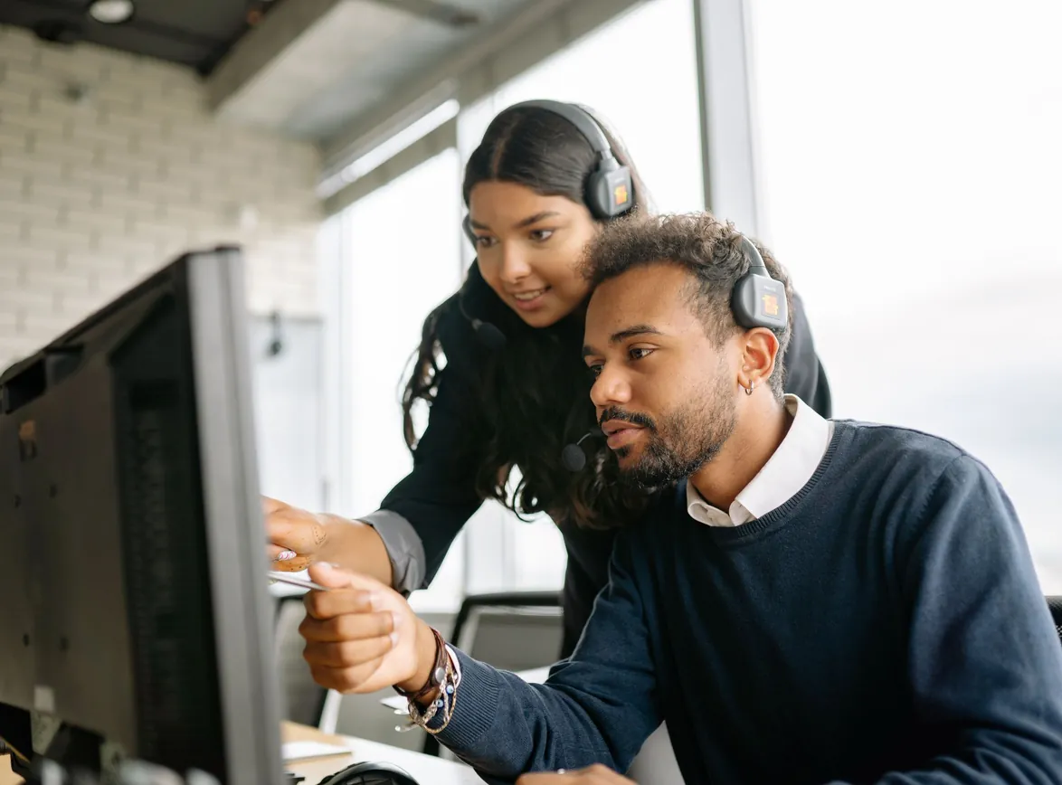 Two call center employees working together with headsets in a modern office setting