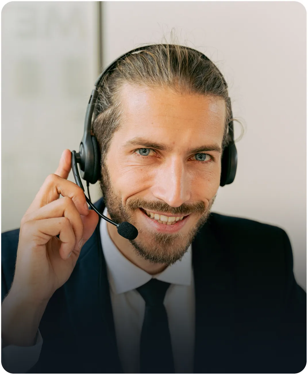 Smiling call center agent in a suit and tie adjusting his headset microphone