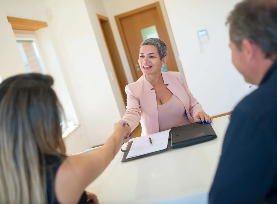Advisor shaking hands with clients at a desk