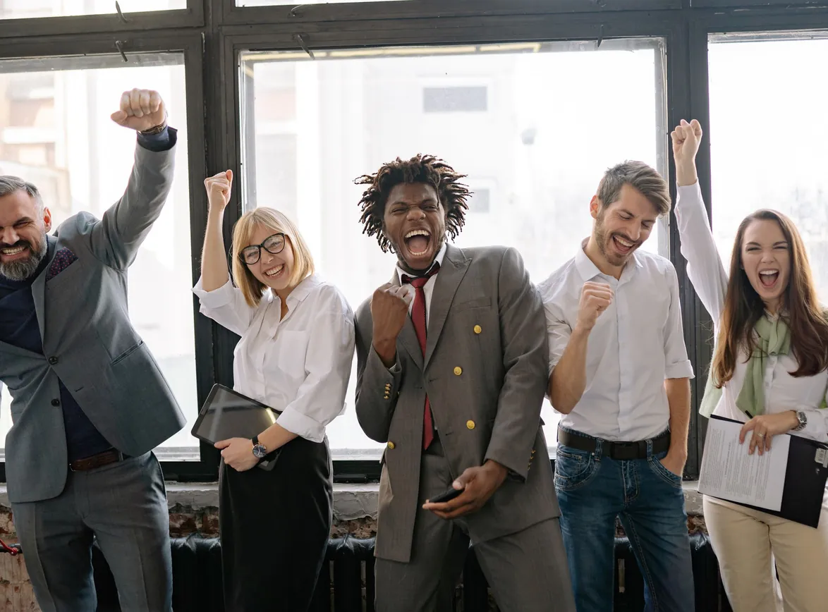A joyful, group of colleagues celebrating success indoors with cheerful expressions