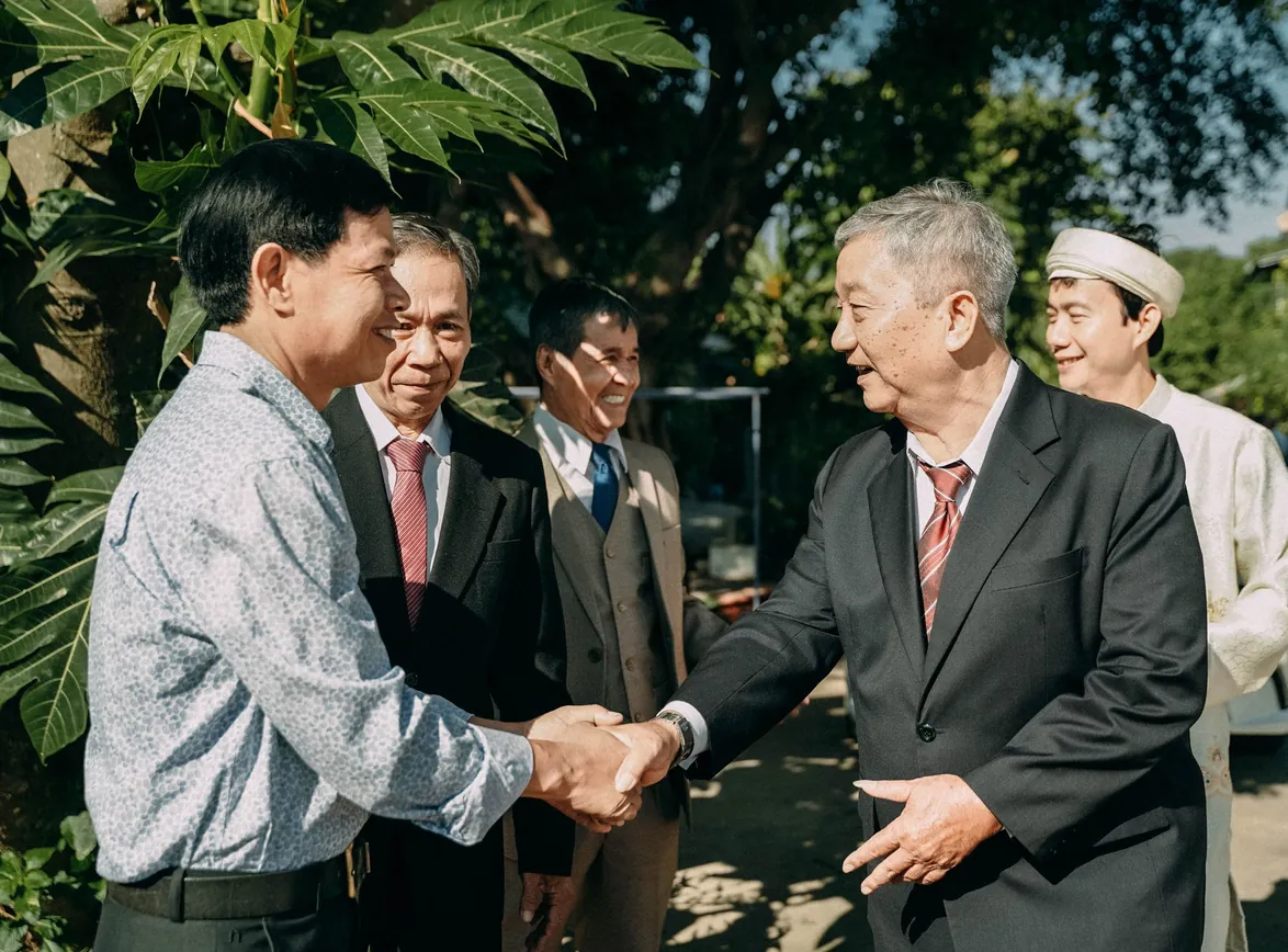 A group of businessmen in formal attire exchanging handshakes in an outdoor setting