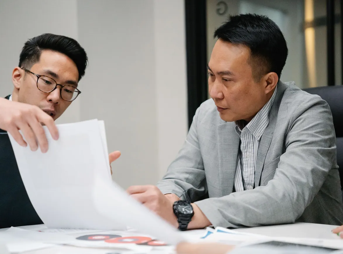 Two professional men engaged in a focused discussion in a contemporary office environment