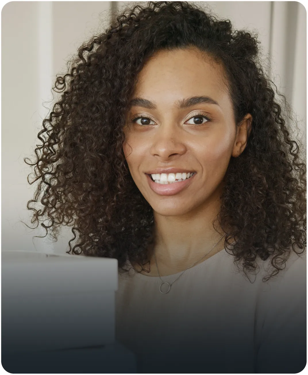 Smiling woman with long curly hair holding a white box
