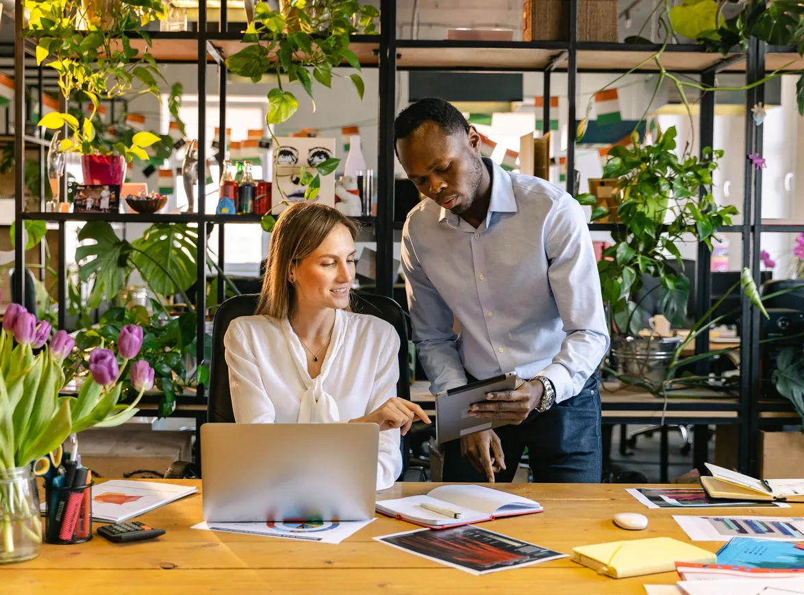 Two professionals engaging in a collaborative discussion in a foliage-filled office