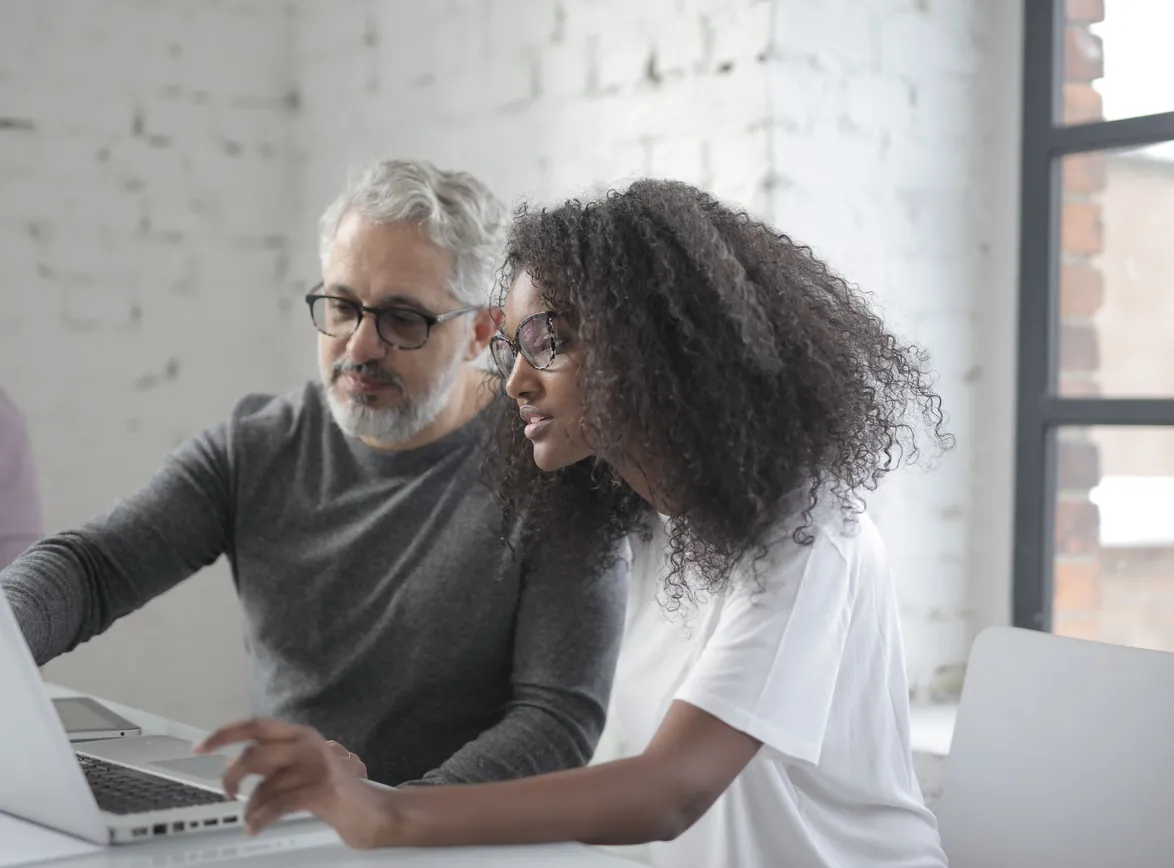Concentrated female and man sitting at table with laptop and working on project