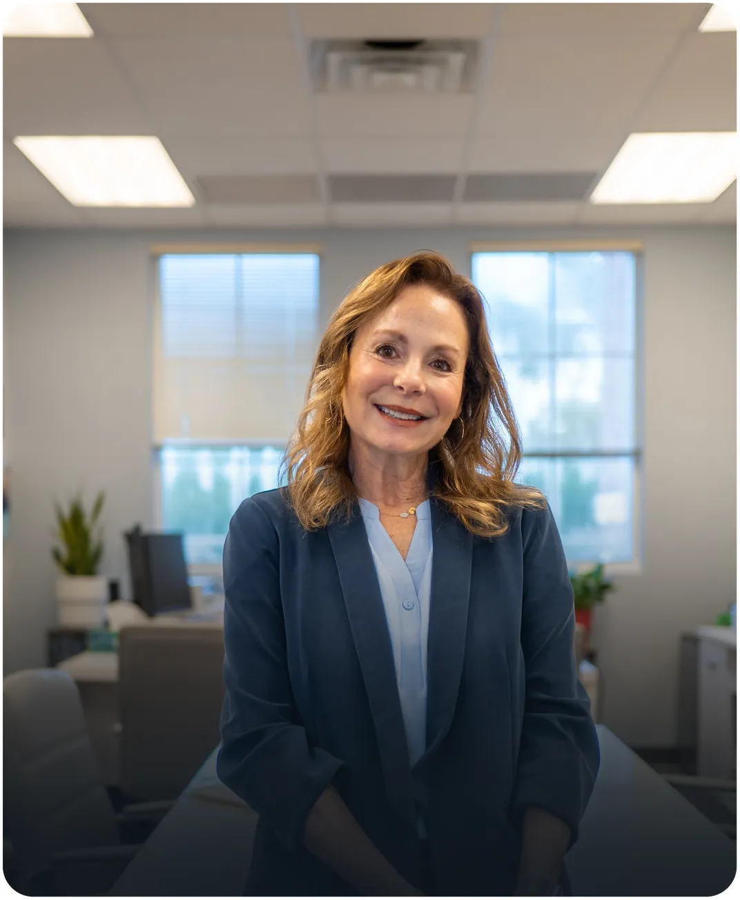 Smiling businesswoman in a navy blazer standing in a bright, open office