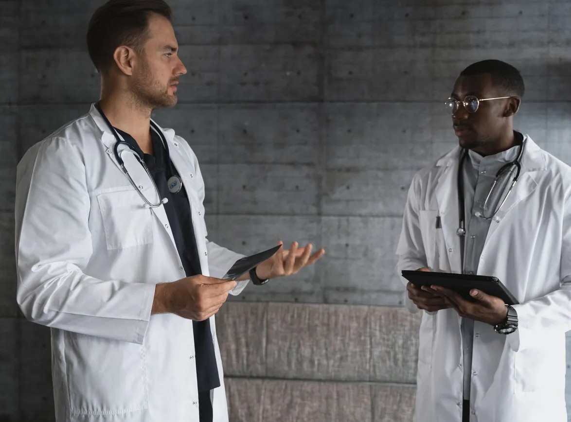 Two doctors in a modern workspace discussing patient care and medical research