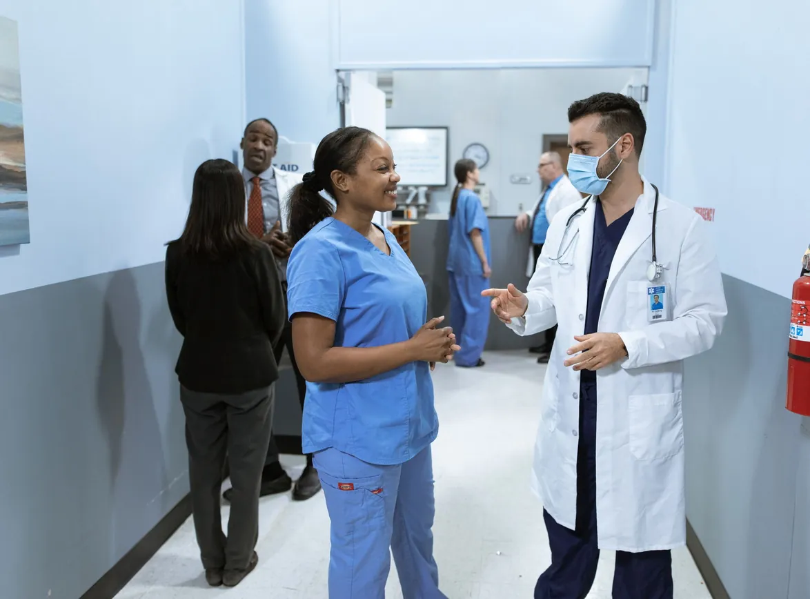 Doctors and nurses in a hospital hallway discussing medical matters