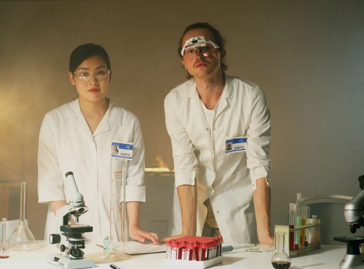 Two scientists conducting experiments in a lab, using microscopes and equipment