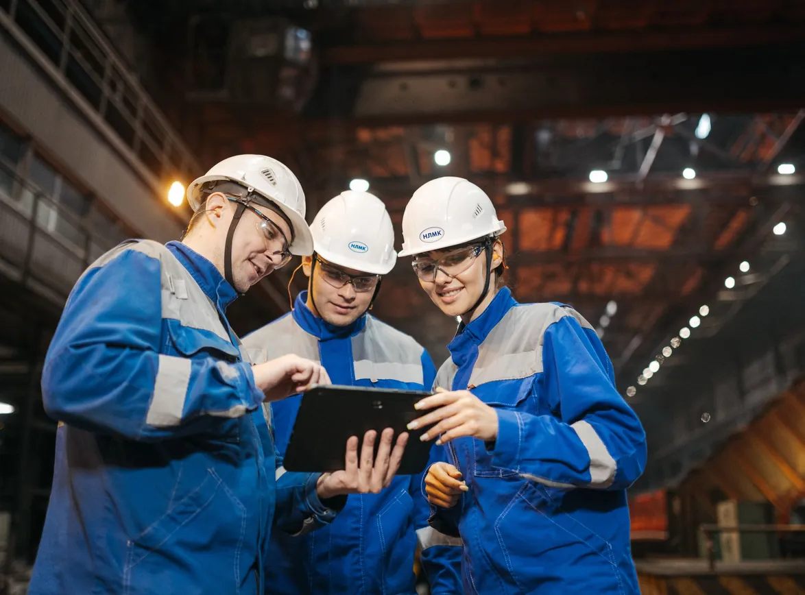 Group of engineers discussing project on a tablet in a factory setting
