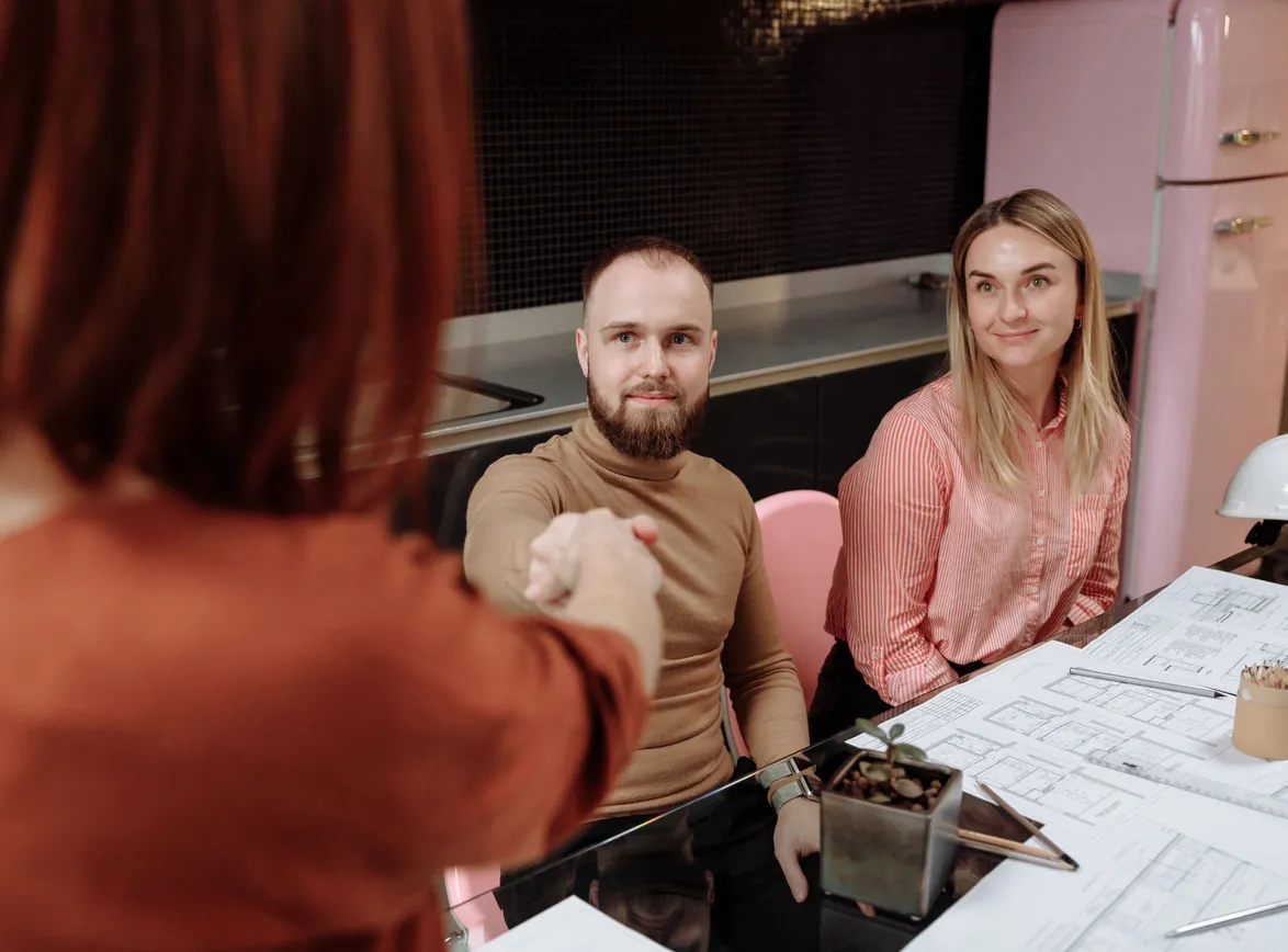 Business professionals sitting around a table during a planning session, engaging in a handshake