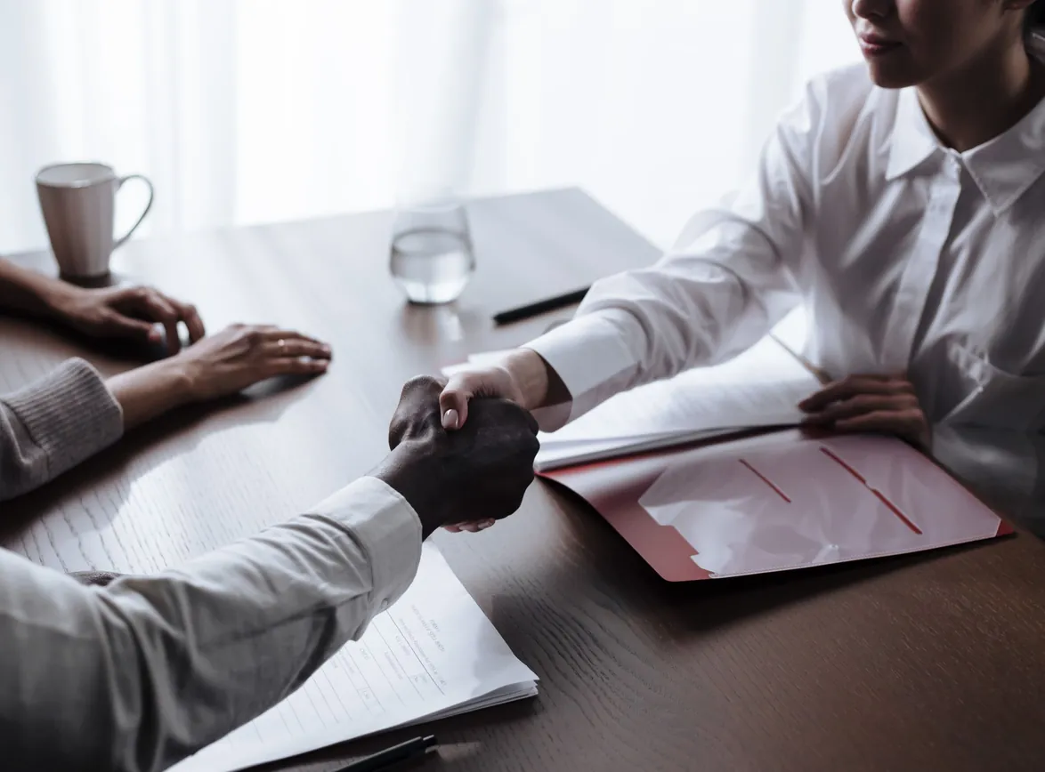 Professional handshake between individuals over a business contract indoors