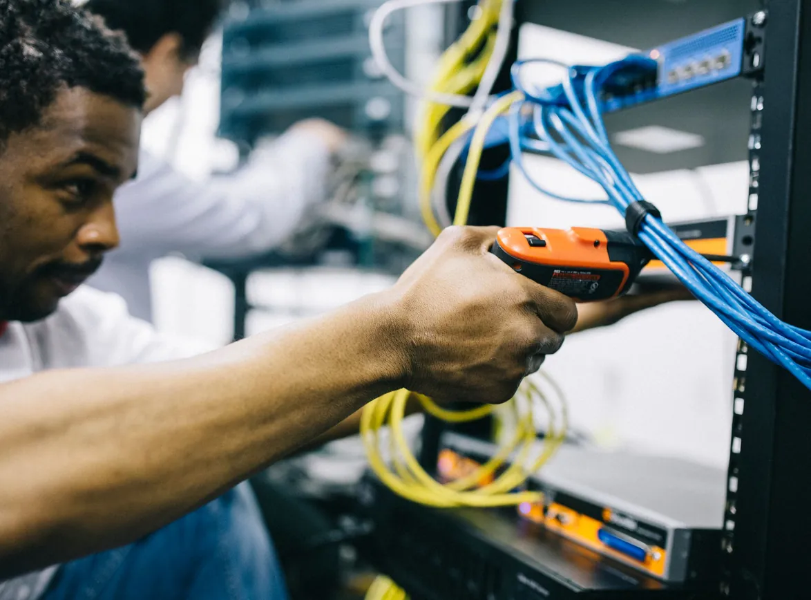 Concentrated Black engineer repairing equipment by using electric screwdriver